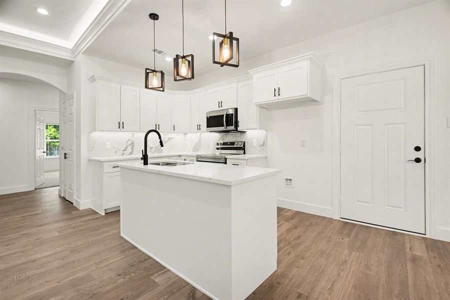 The kitchen features a central island, white cabinetry, a white countertop, and stainless steel appliances