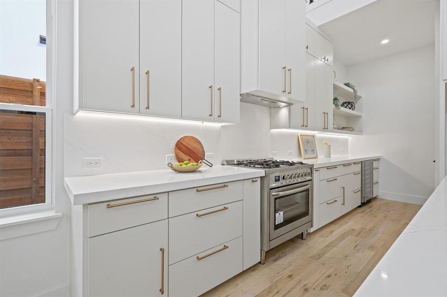 Kitchen featuring stainless steel range, white cabinetry, and light hardwood / wood-style floors