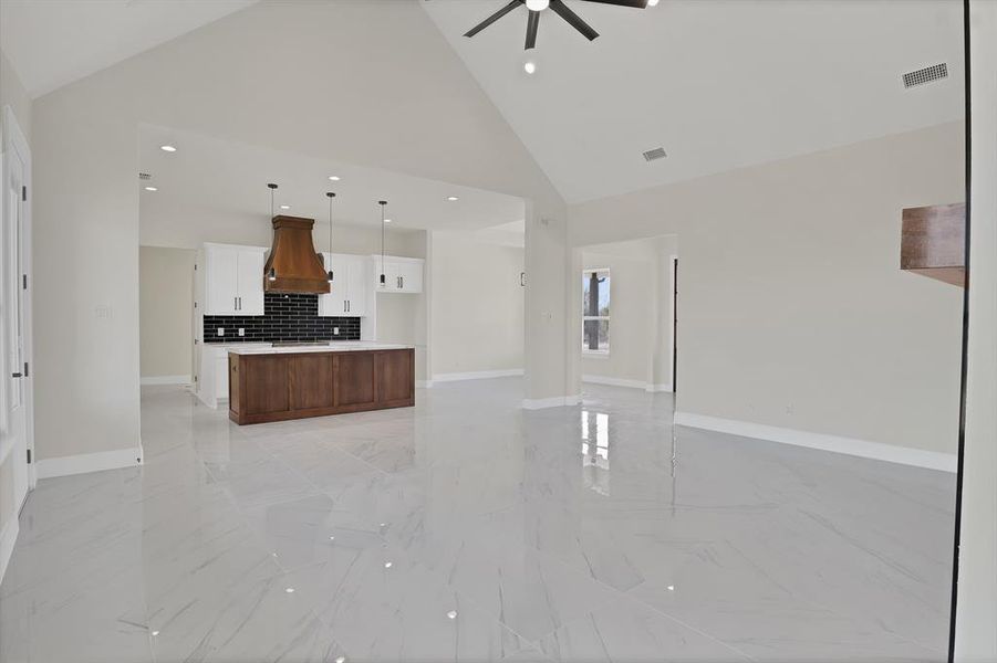 Unfurnished living room featuring ceiling fan, sink, and high vaulted ceiling