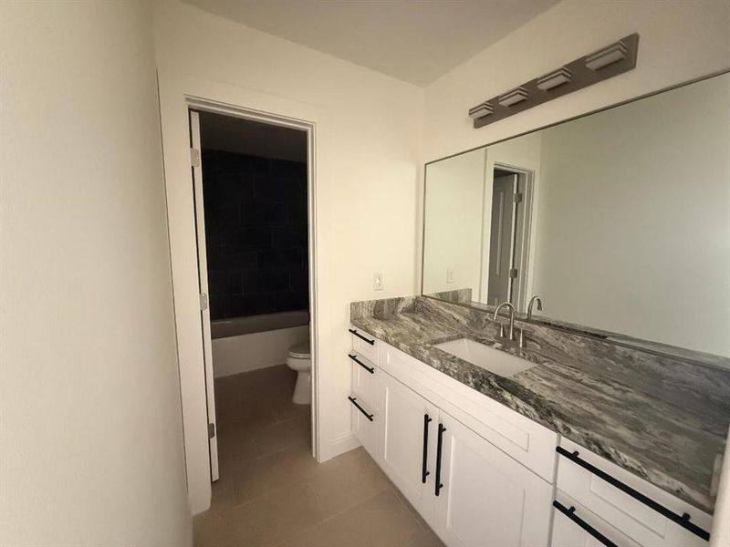 Full bath featuring vanity and dark tile patterned floors