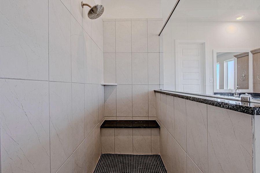 Walk-in shower with tile surround and glass enclosure.
