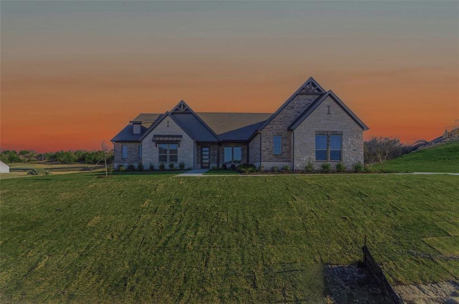 View of front of property with stone siding and a yard