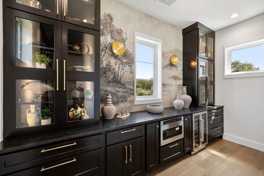 Elegant dark cabinetry and stone countertops offer a stylish beverage station with scenic window views.