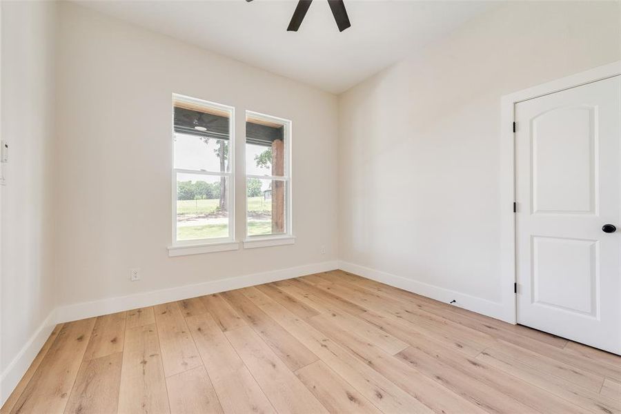 Spacious room featuring wood-finish flooring, white baseboards, and neutral wall tones