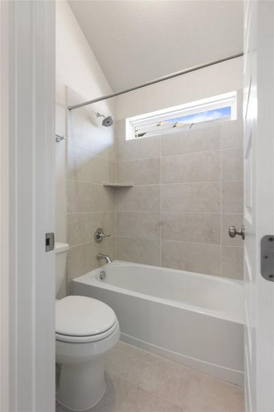 Full bathroom with  shower combination, light tile patterned flooring, and lofted ceiling
