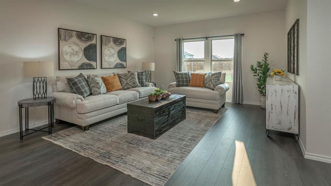 Open-concept living area featuring wood-finish flooring, recessed lighting, and a large window with ample natural light