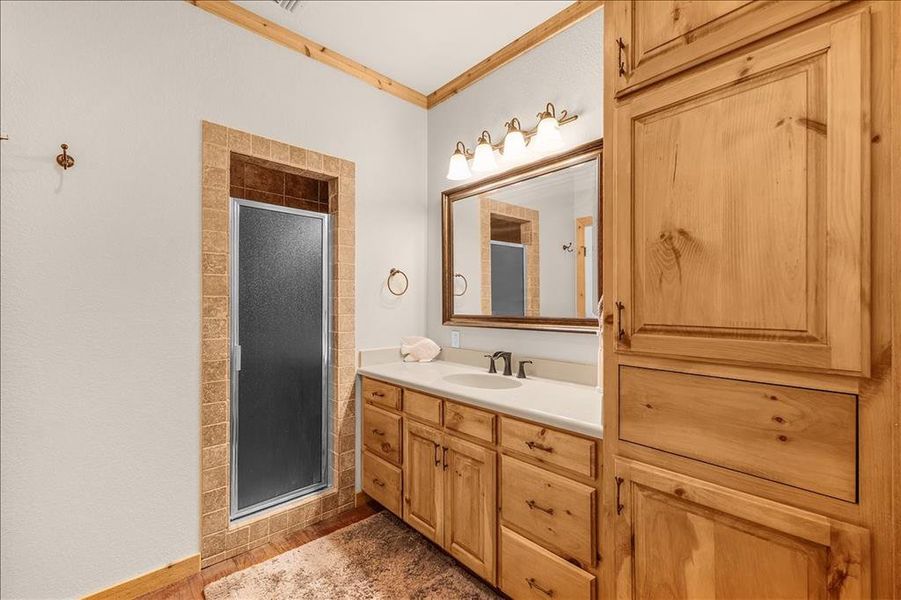 Full bathroom featuring crown molding, vanity, and a stall shower