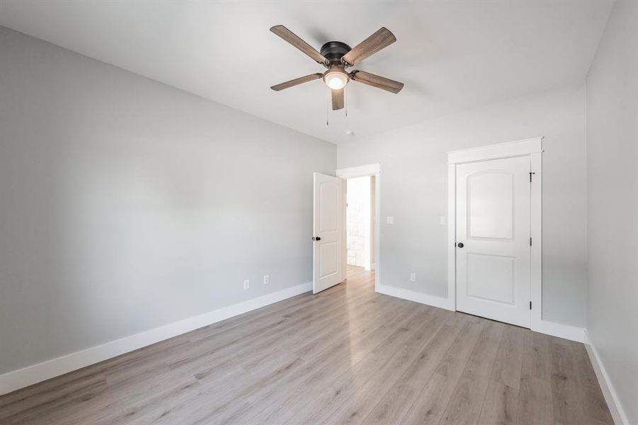 Unfurnished bedroom with ceiling fan and light wood-type flooring