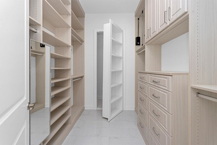 The custom walk-in closets offers abundant built-in storage, soft-close drawers, and a hidden safe room concealed behind a clever bookshelf door for ultimate peace of mind. The custom walk-in closets offers abundant built-in storage, soft-close drawers, and a hidden safe room concealed behind a clever bookshelf door for ultimate peace of mind.