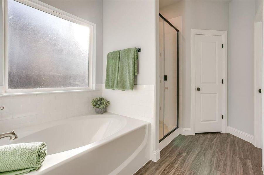 Bathroom featuring a bath, dark wood-type flooring, and a shower stall