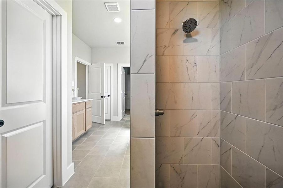 Full bath featuring a tile shower, vanity, and light tile patterned floors
