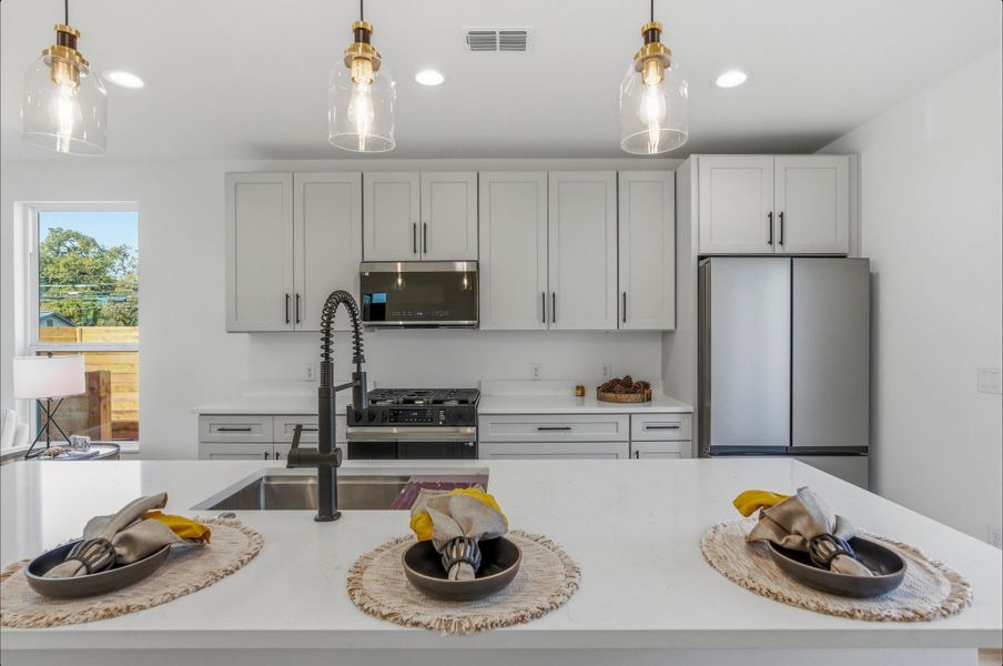 Kitchen featuring light stone countertops, pendant lighting, stainless steel appliances, a kitchen island with sink, and recessed lighting
