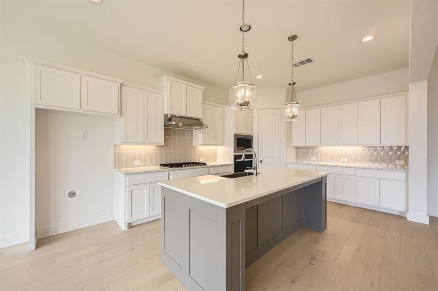Kitchen featuring a sink, stainless steel appliances, under cabinet range hood, tasteful backsplash, and recessed lighting