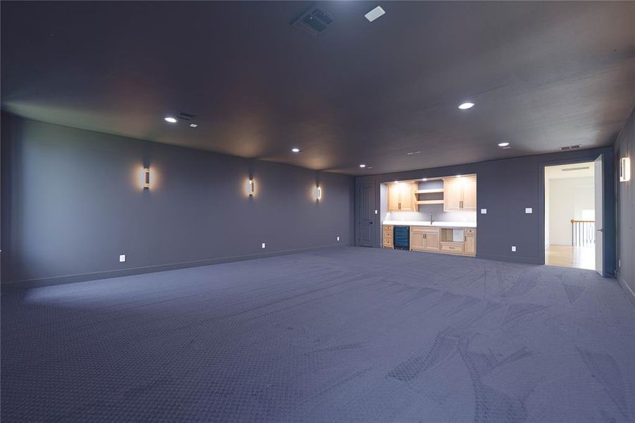 Unfurnished living room featuring carpet flooring, baseboards, recessed lighting, a sink, and beverage cooler Unfurnished living room featuring carpet flooring, baseboards, recessed lighting, a sink, and beverage cooler