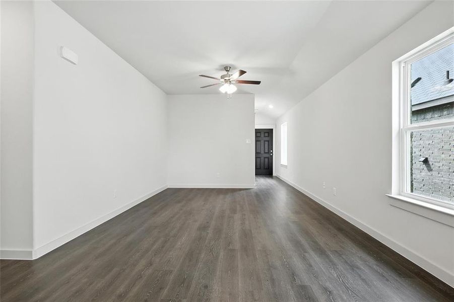 Spare room featuring a ceiling fan, dark wood-style flooring, and lofted ceiling Spare room featuring a ceiling fan, dark wood-style flooring, and lofted ceiling
