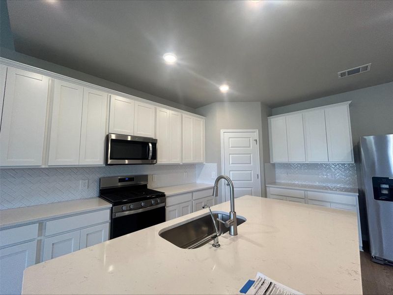 Kitchen featuring appliances with stainless steel finishes, backsplash, white cabinets, recessed lighting, and light stone counters Kitchen featuring appliances with stainless steel finishes, backsplash, white cabinets, recessed lighting, and light stone counters