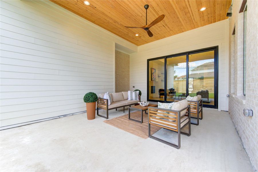 Designed for year-round enjoyment, the expansive covered patio serves as a natural extension of the home's interior living spaces. A soaring tongue-and-groove wood ceiling, designer ceiling fan, and contemporary finishes create a warm yet sophisticated outdoor retreat. Oversized sliding glass doors seamlessly connect the family room to the patio, enhancing the home's indoor-outdoor lifestyle and making entertaining effortless.