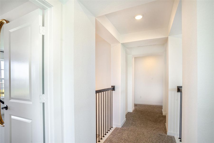Bright and open hallway with carpeted flooring, recessed lighting, and a modern railing. It connects to multiple rooms, creating a welcoming and airy feel. Bright and open hallway with carpeted flooring, recessed lighting, and a modern railing. It connects to multiple rooms, creating a welcoming and airy feel.