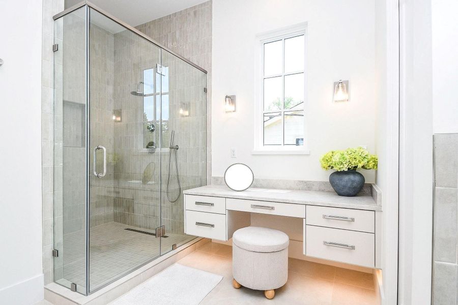 This bathroom features a spacious glass-enclosed shower with modern fixtures, a sleek vanity with ample storage, and a bright window providing natural light. The neutral color palette and elegant finishes create a fresh, inviting atmosphere.
