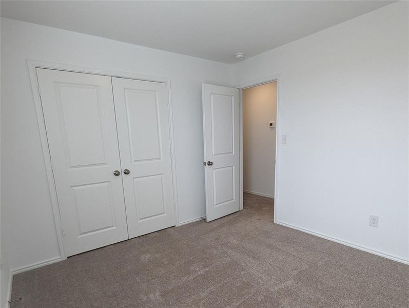 A well-lit room features plush carpeting and classic white double-panel doors, offering comfort and style.