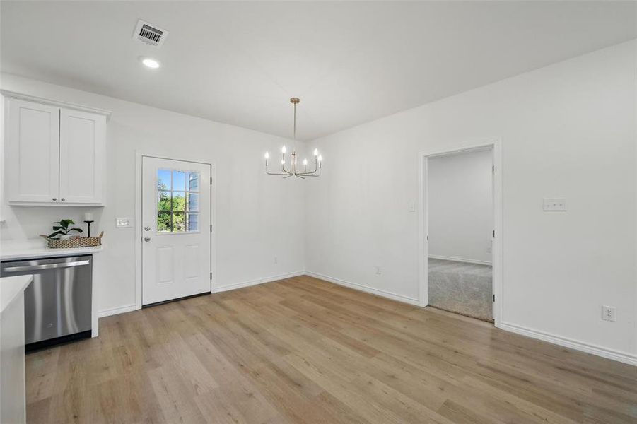 Unfurnished dining area featuring light wood-style flooring, a chandelier, and baseboards Unfurnished dining area featuring light wood-style flooring, a chandelier, and baseboards