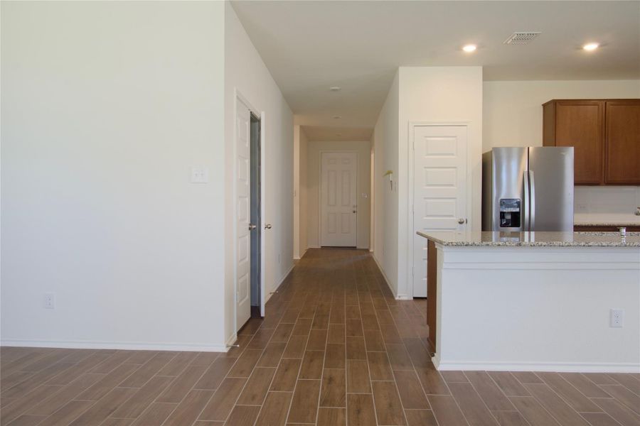 A welcoming entryway with rich wood-look tile flooring leads to an inviting kitchen with granite counters.
