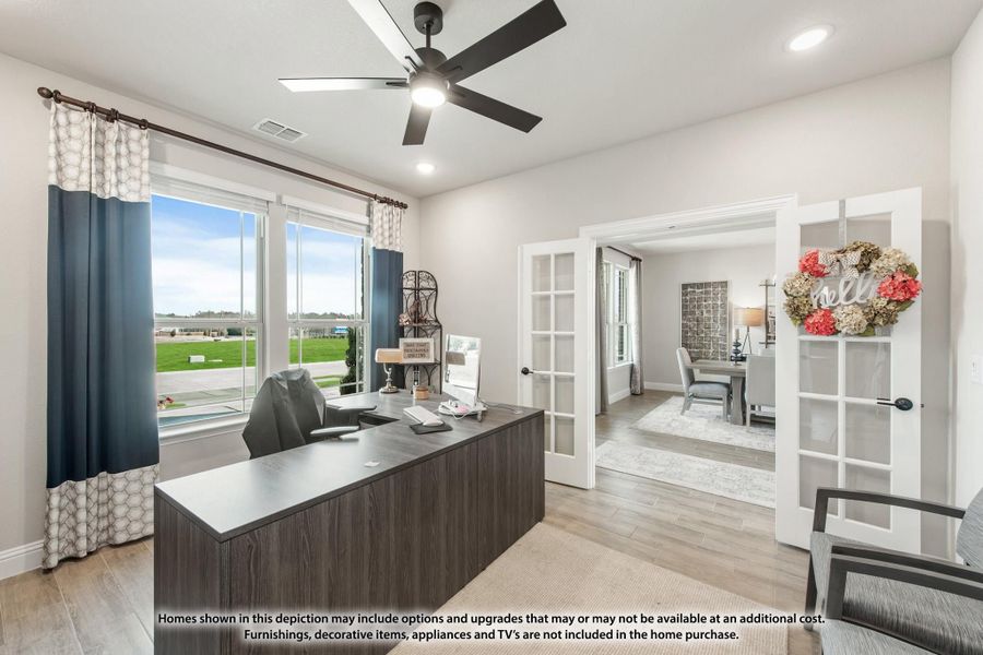 Home office with dark wood desk, ceiling fan, French doors, and large window with backyard view Home office with dark wood desk, ceiling fan, French doors, and large window with backyard view