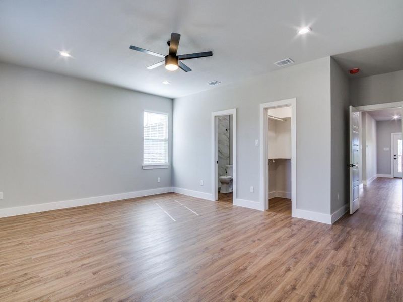 Unfurnished bedroom featuring ceiling fan, ensuite bathroom, light hardwood / wood-style floors, a walk in closet, and a closet