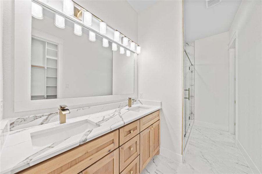 Full bathroom featuring a marble finish shower, light marble finish flooring, and double vanity Full bathroom featuring a marble finish shower, light marble finish flooring, and double vanity