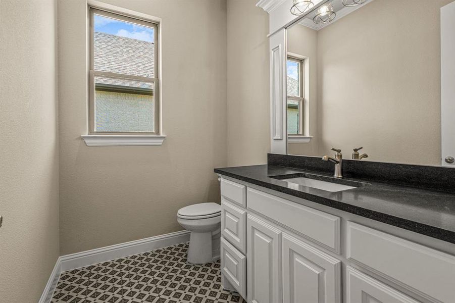 Bathroom featuring a wealth of natural light, toilet, vanity, and tile patterned floors