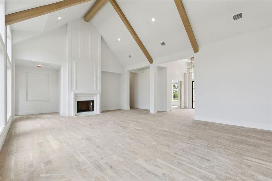 Natural light fills the great room with a cathedral ceiling displaying beautiful wood beams, two-story fireplace, and floor to ceiling windows overlooking your outdoor retreat.