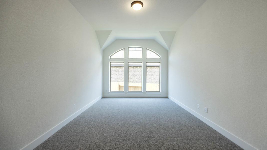 Unfurnished room with carpet flooring, baseboards, a textured wall, and vaulted ceiling Unfurnished room with carpet flooring, baseboards, a textured wall, and vaulted ceiling