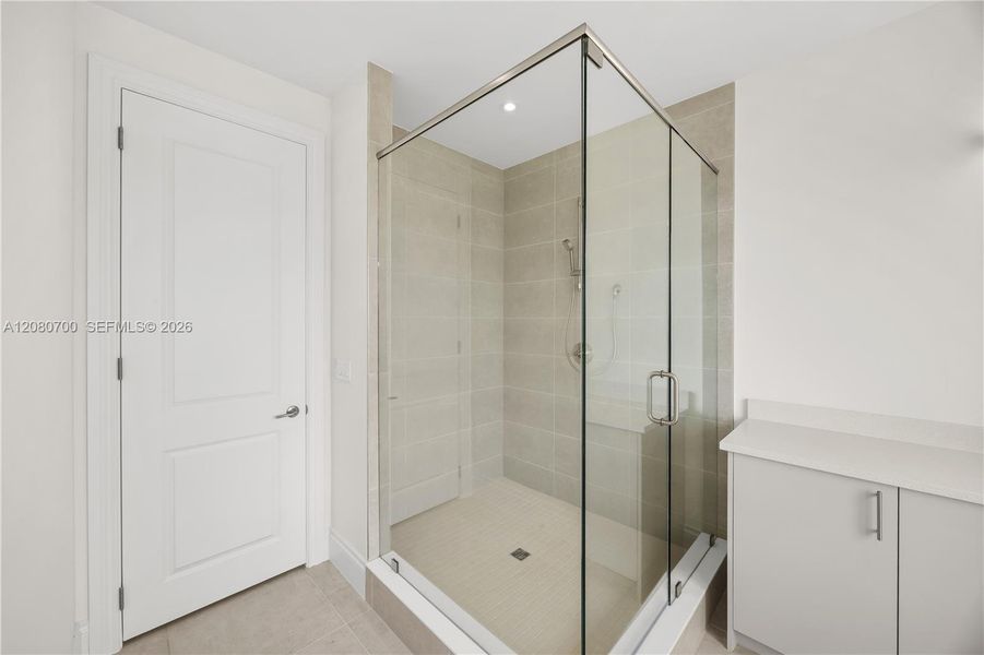 Glass-enclosed shower with a built-in bench, tiled walls, and a rainfall showerhead
