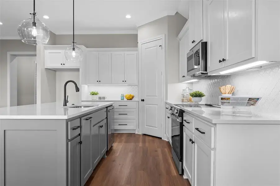 Kitchen featuring white cabinetry, backsplash, an island with sink, gray cabinets, and crown molding Kitchen featuring white cabinetry, backsplash, an island with sink, gray cabinets, and crown molding