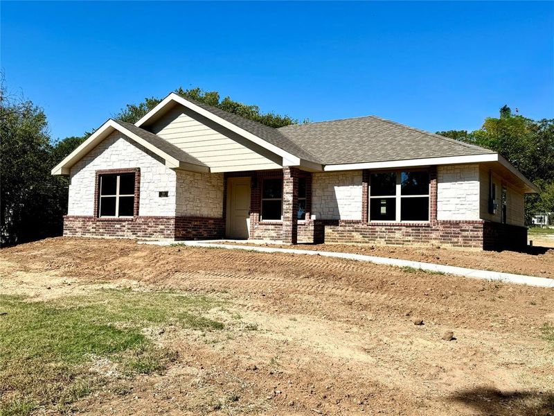 Ranch-style home featuring brick siding, a shingled roof, and a front lawn