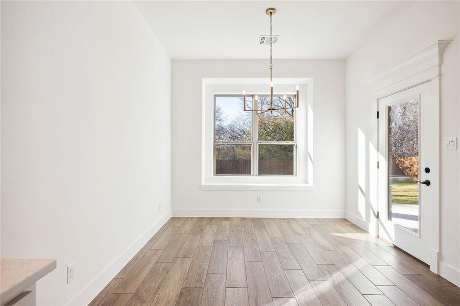 Unfurnished dining area featuring light hardwood / wood-style floors and an inviting chandelier