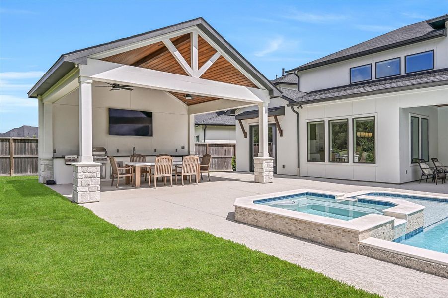 A separate covered outdoor kitchen pavilion overlooks the pool & spa, boasting a vaulted wood-plank ceiling, stone-accented columns, mounted TV, generous dining space and a fully equipped grilling station.