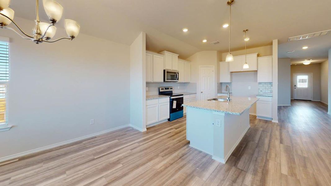 Kitchen with white cabinets, stainless steel appliances, backsplash, a center island with sink, and light wood-style floors Kitchen with white cabinets, stainless steel appliances, backsplash, a center island with sink, and light wood-style floors