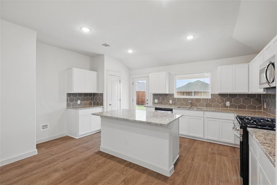 Kitchen with lofted ceiling, visible vents, stainless steel appliances, and light wood-style floors Kitchen with lofted ceiling, visible vents, stainless steel appliances, and light wood-style floors