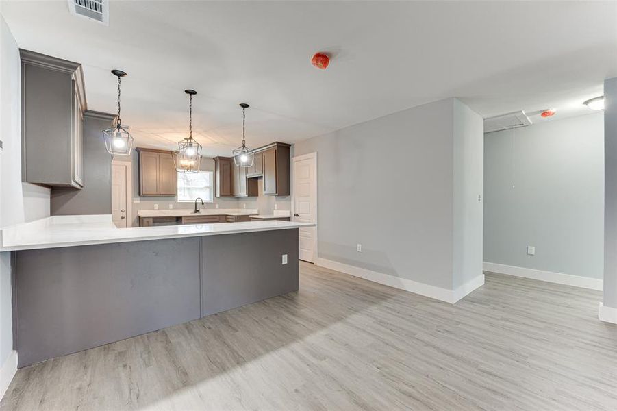 Kitchen featuring sink, pendant lighting, light wood-type flooring, and kitchen peninsula