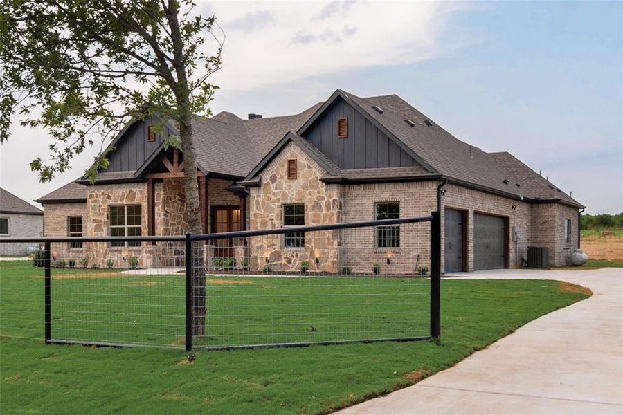 View of front of house featuring board and batten siding, concrete driveway, roof with shingles, brick siding, and stone siding View of front of house featuring board and batten siding, concrete driveway, roof with shingles, brick siding, and stone siding