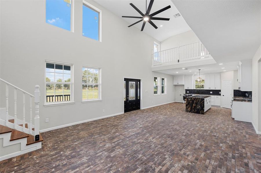 Unfurnished living room featuring stairs, recessed lighting, a ceiling fan, and a towering ceiling Unfurnished living room featuring stairs, recessed lighting, a ceiling fan, and a towering ceiling