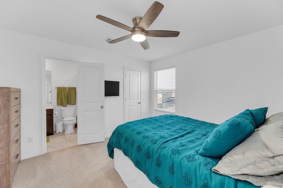 Bedroom featuring ceiling fan, connected bathroom, and light carpet
