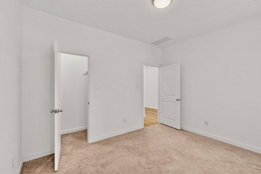 Unfurnished bedroom with a walk in closet and light colored carpet Unfurnished bedroom with a walk in closet and light colored carpet