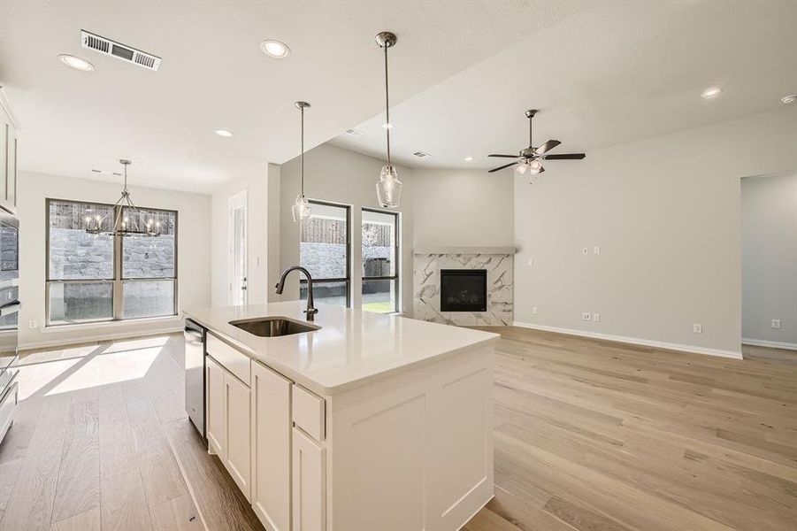 Kitchen with a center island with sink, white cabinetry, a high end fireplace, light wood-type flooring, and sink