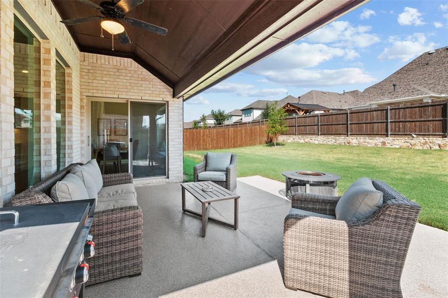 Fenced backyard with an outdoor living space with a fire pit, a patio, and ceiling fan