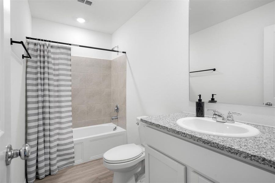 Bathroom with vanity, shower / bath combo with shower curtain, and light wood-type flooring Bathroom with vanity, shower / bath combo with shower curtain, and light wood-type flooring