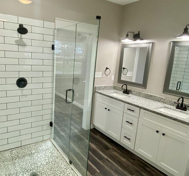 Bathroom with hardwood / wood-style flooring, a shower with door, and vanity