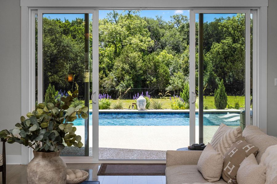 Sliding glass doors offer an immersive view of the inviting pool and lush backyard sanctuary.