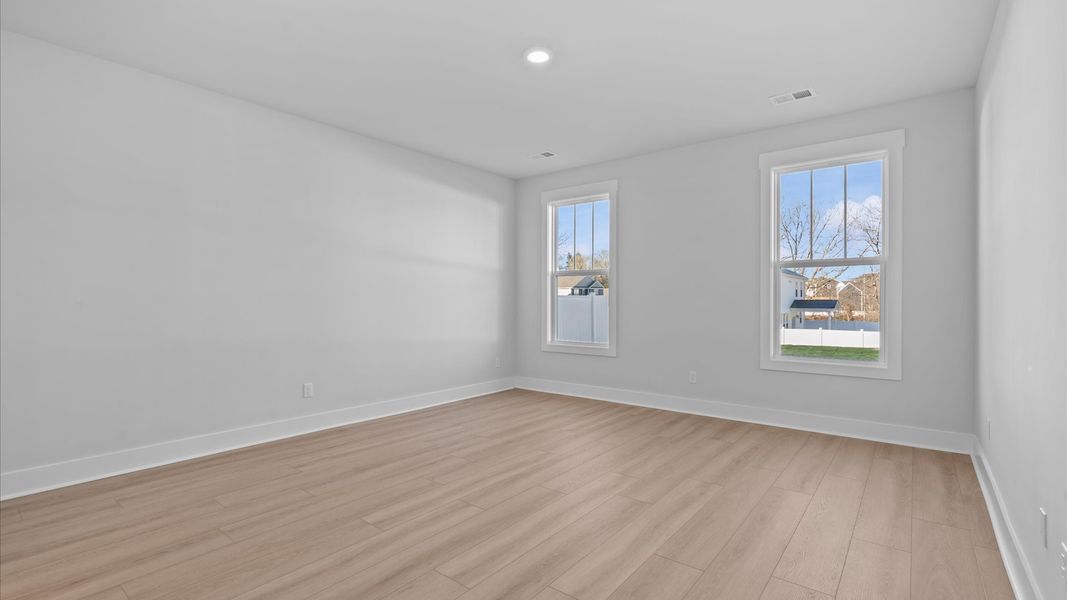 Serene and stylish primary bedroom featuring hardwood flooring and a thoughtful, modern layout